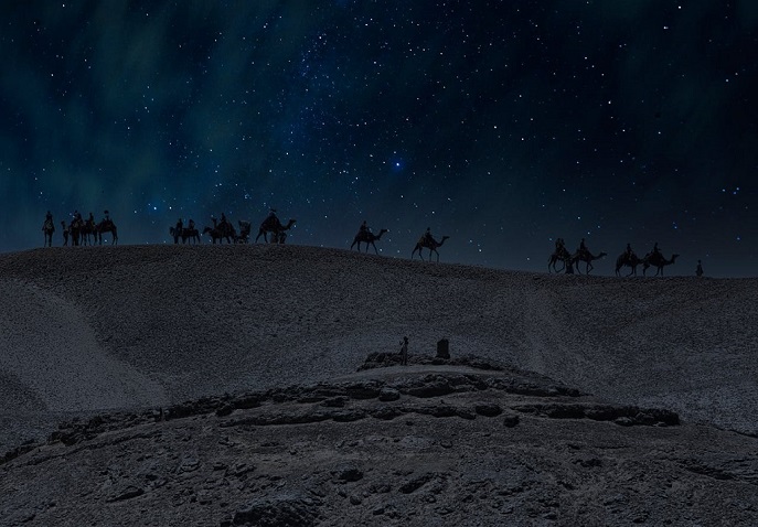 Camel caravan silhouetted against a starry desert sky