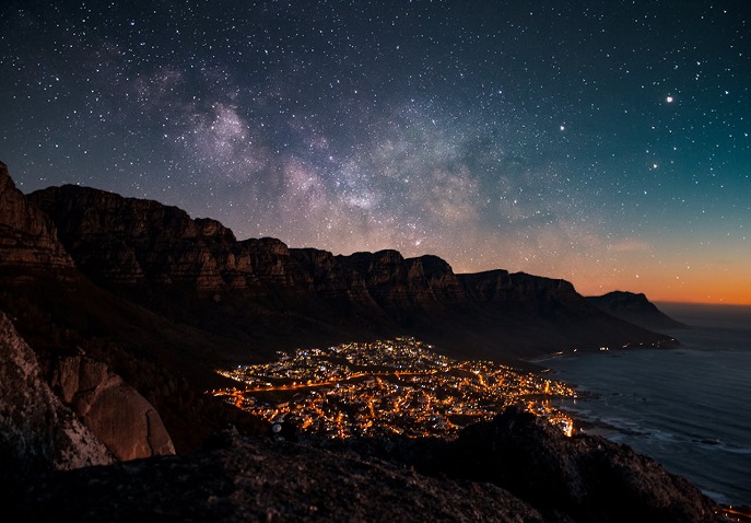 Mighty ocean beneath the star-lit sky, surrounded by mountains and illuminated beach