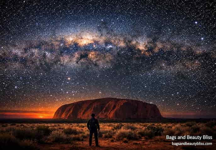 Traveler gazing at the Milky Way above Uluru in Australia's desert night sky, cinematic travel photography evoking wonder and reflection. Uluru Stargazing – Australia’s Desert Night Sky Experience