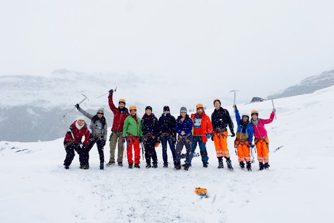 A group of adventurous women bundled in winter gear, hiking through Iceland’s snowy wilderness, smiling and bonding amid dramatic landscapes—celebrating strength, sisterhood, and empowerment in nature.