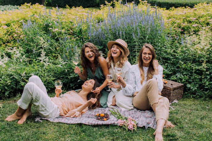 Women enjoying a joyful garden picnic in the French countryside, surrounded by blooming flowers, champagne glasses in hand—capturing pure happiness, connection, and the elegance of feminine celebration.