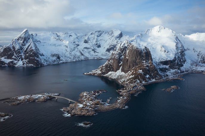 Arctic landscape with jagged snow-covered peaks surrounding icy fjords in East Greenland