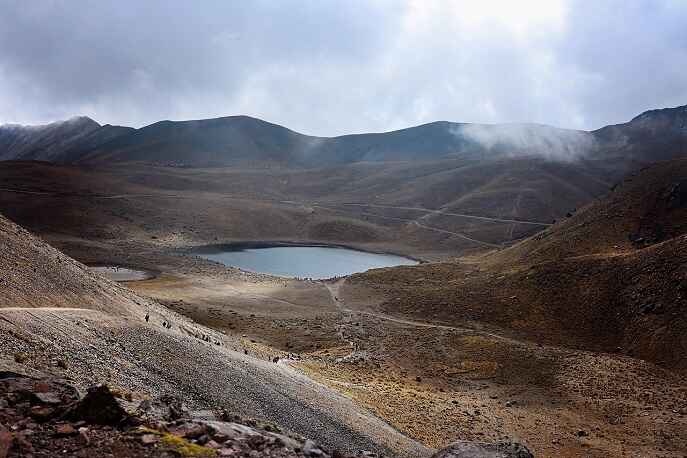 Misty view of a lake surrounded by rocky terrain in the Fann Mountains, Tajikistan