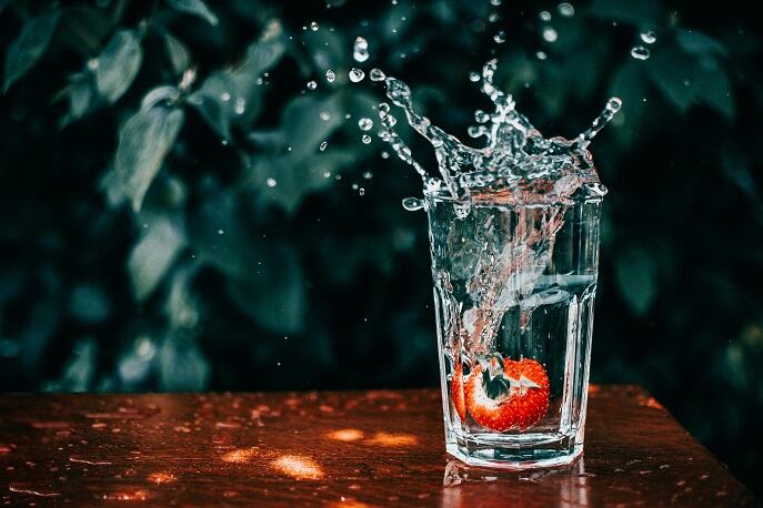 Clear splashing from a glass of fresh water with a fruit inside.