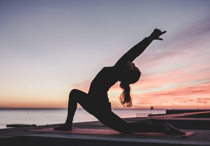 Woman practicing yoga at sunrise near the Ganges in Rishikesh, India during a budget-friendly women-only spiritual retreat focused on meditation and healing
