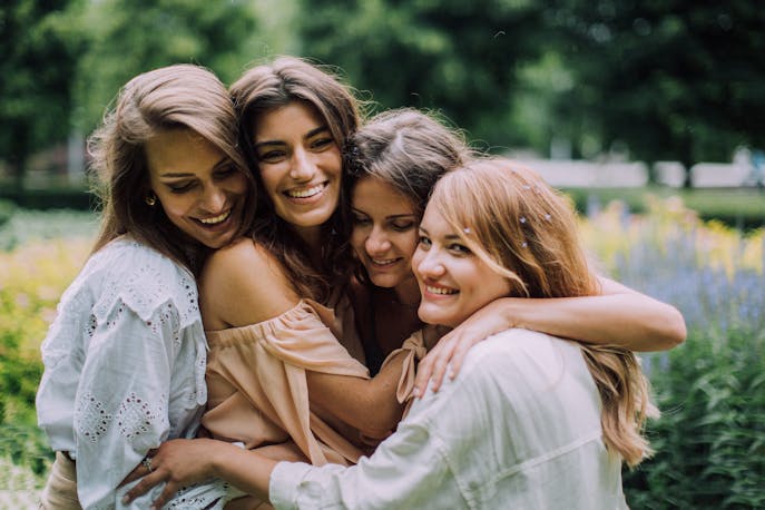 A joyful group of women walking through Australia’s blooming spring gardens, laughing and holding hands—celebrating sisterhood, renewal, and the beauty of deep connections in nature.