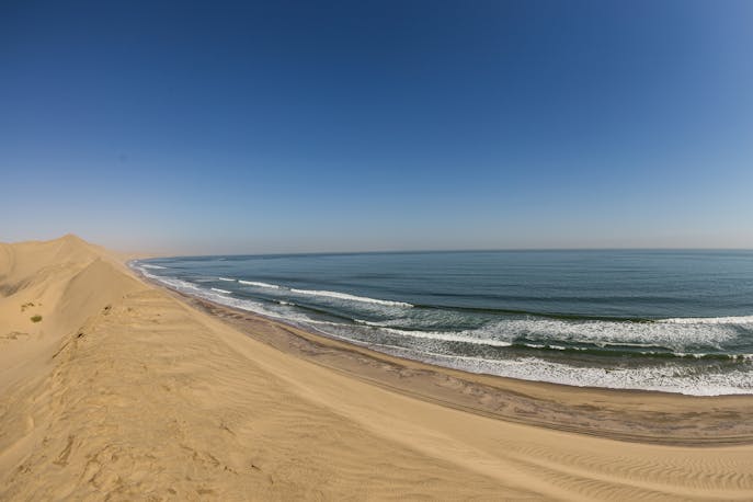 Expansive view of sand dunes meeting the Atlantic Ocean at Skeleton Coast, Namibia.