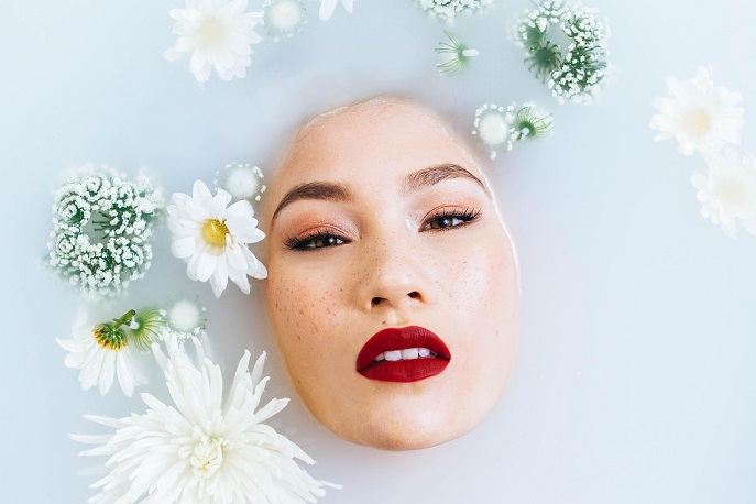 Woman with glowing skin and flowers in a milk bath