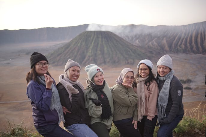 Smiling women wrapped in scarves, standing against the stunning volcanic backdrop of Bali, capturing moments of laughter, connection, and soulful sisterhood during a scenic mountain getaway.