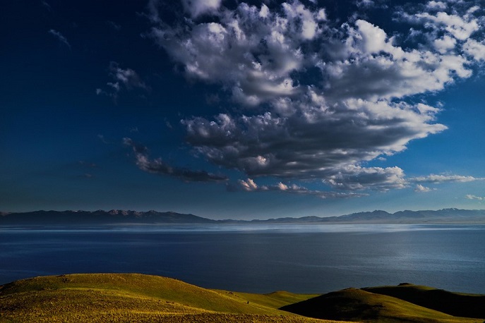 Tranquil high-altitude Song-Köl Lake under dramatic skies in Kyrgyzstan.