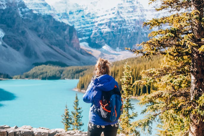 Woman in a blue jacket gazing at glacial lakes and snowy peaks, finding strength through solo travel