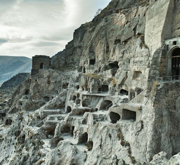Ancient city carved into rocky mountain cliffs showcasing intricate cave dwellings and stone stairways.