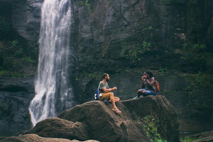 Couple enjoying a cozy travel moment near a waterfall with mountain views – budget-friendly and romantic travel tips for couples.