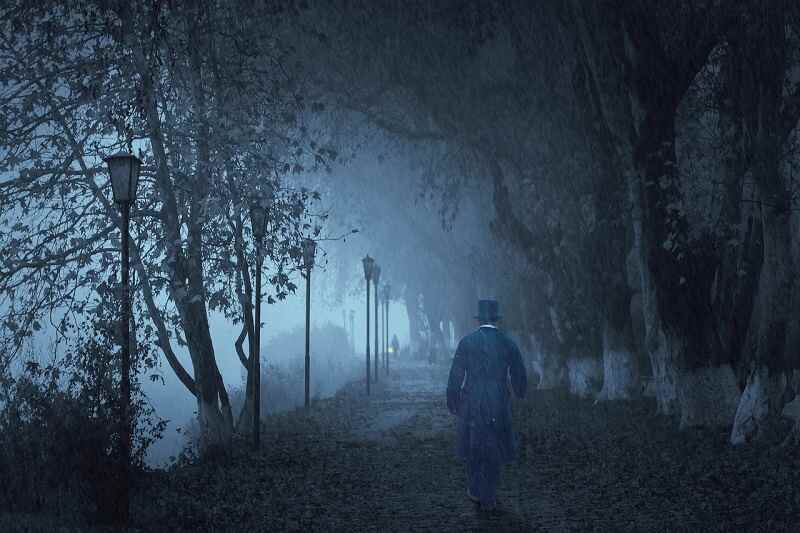 A mysterious man walking in the woods while it is raining.