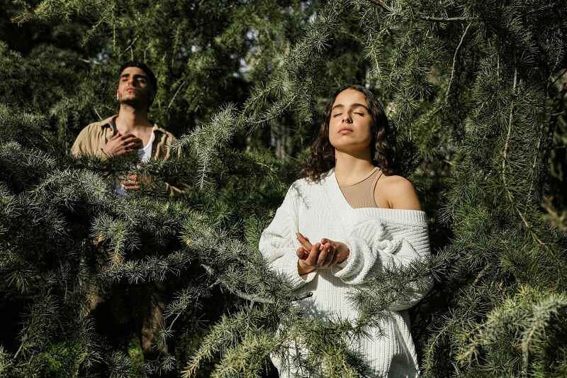 A couple meditating and relaxing amidst green trees to reconnect with nature