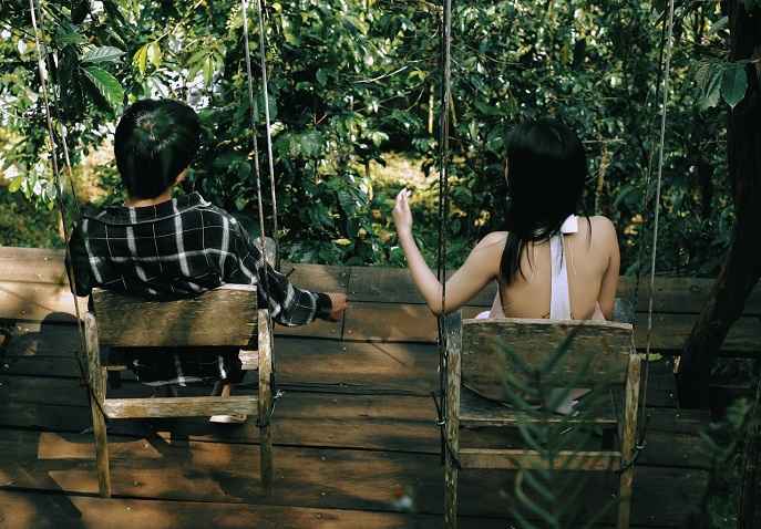 A couple relaxing on a wooden platform on chairs surrounded by greenery during a Valentine’s wellness travel retreat