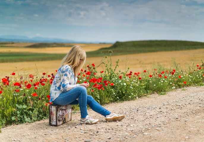 Woman sitting alone in a flower field reflecting before solo travel after 40.