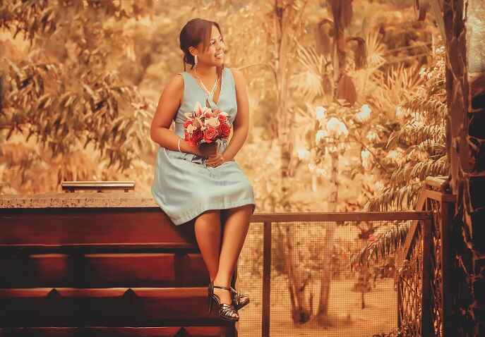 Solo woman holding flowers while sitting peacefully in a garden setting