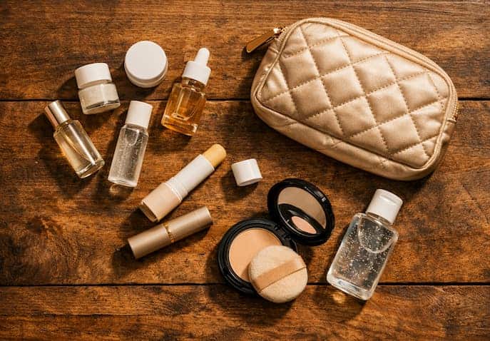 Flat lay of mini skincare, lip balm, sanitizer, and compact pouch styled in cinematic tones.